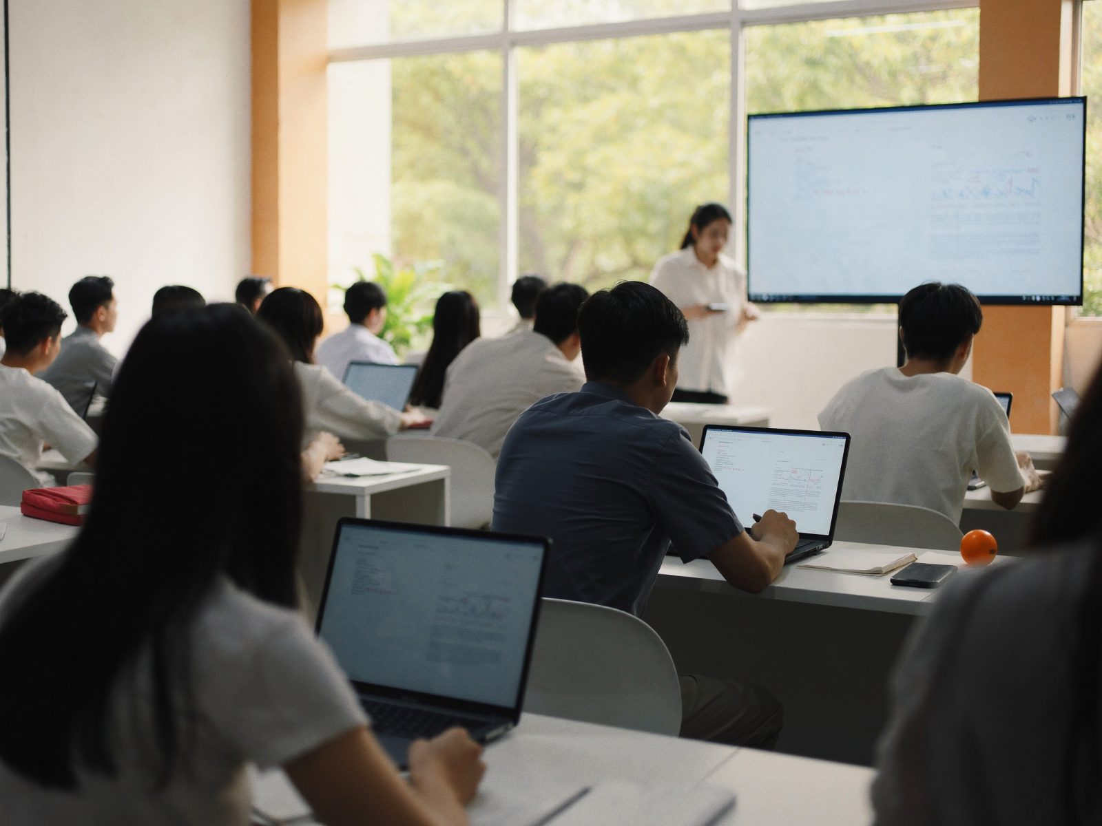 Lớp học đông học viên tại một trung tâm ngoại ngữ, giáo viên giảng bài bên màn hình lớn